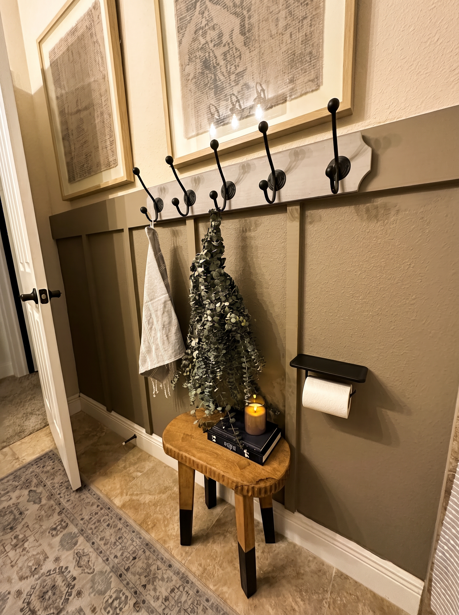 Bathroom hallway detail with board-and-batten wall, iron hook rail, eucalyptus, wooden stool with stacked books and candle — Lithia, FL