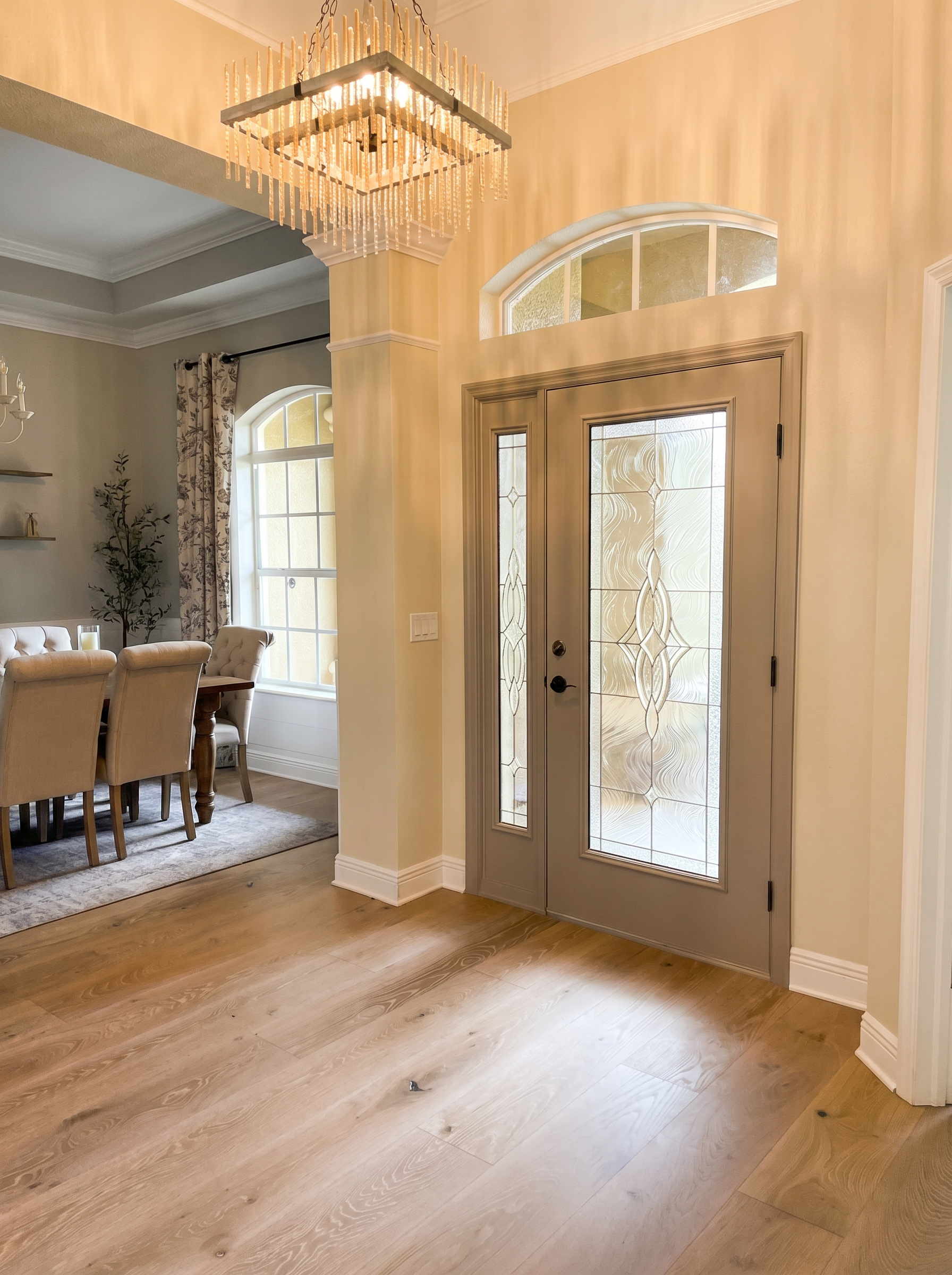 Grand foyer with wide-plank white oak floors, crystal-and-brass chandelier, and arched transom entry door — Lithia, FL
